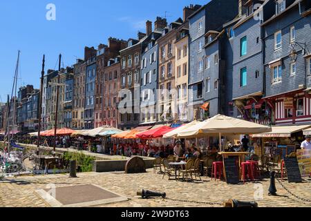 Honfleur, Francia - 24 luglio 2022: Case e ristoranti nel vecchio porto di Honfleur in una giornata di sole in estate, cielo blu Foto Stock