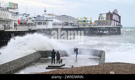 Brighton Regno Unito 27 dicembre 2023 - i visitatori si bagnano mentre le onde si infrangono sul lungomare di Brighton vicino al molo mentre Storm Gerrit batte la Gran Bretagna oggi con avvisi meteo emessi in tutto il paese : Credit Simon Dack / Alamy Live News Foto Stock