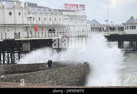 Brighton Regno Unito 27 dicembre 2023 - i visitatori si bagnano mentre le onde si infrangono sul lungomare di Brighton vicino al molo mentre Storm Gerrit batte la Gran Bretagna oggi con avvisi meteo emessi in tutto il paese : Credit Simon Dack / Alamy Live News Foto Stock