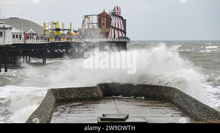 Brighton Regno Unito 27 dicembre 2023 - i visitatori si bagnano mentre le onde si infrangono sul lungomare di Brighton mentre Storm Gerrit batte la Gran Bretagna oggi con avvisi meteo emessi in tutto il paese : Credit Simon Dack / Alamy Live News Foto Stock