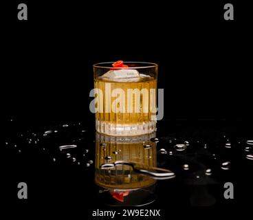 Bicchiere di whisky con cubetti di ghiaccio su sfondo nero e gocce d'acqua Foto Stock