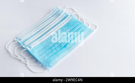 Set di maschere chirurgiche con fasce auricolari in gomma per la protezione contro l'influenza e i virus su sfondo bianco. Foto Stock