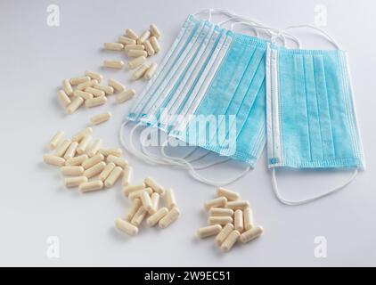 Maschere protettive mediche con pillole su sfondo bianco. Foto Stock