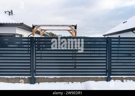 Una moderna recinzione color antracite, un parco giochi visibile fatto di cubi di legno. Foto Stock