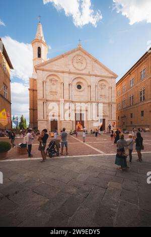 Pienza, Italia - 31 agosto 2023: I turisti e gli abitanti del luogo apprezzano la colorata piazza principale della città vecchia, Piazza Pio II e il Duomo di Santa Maria Assunta Foto Stock