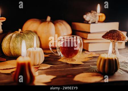 Tazza di tè in vetro tra candele di zucca. Contenuti a tema autunnale, promozioni per i caffè Foto Stock