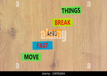 Muoviti in fretta e rompi il simbolo. Le parole concettuali si muovono velocemente e si rompono su carta colorata. Splendido sfondo in legno. Affari, muoviti in fretta e in libertà Foto Stock