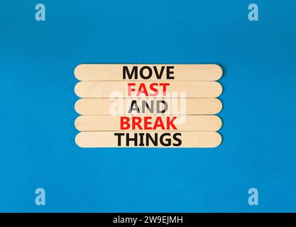 Muoviti in fretta e rompi il simbolo. Le parole concettuali si muovono velocemente e rompono le cose su un bastone di legno. Bellissimo sfondo blu. Affari, muoviti in fretta Foto Stock