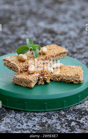 chiudi il mazzo di sesamo con sudore di zucchero scuro e semi di noci di pisello, menta verde sulla scatola di plastica verde, sfondo marrone grigio naturale. Foto Stock