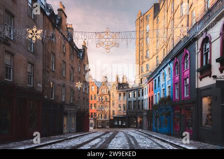 Decorazioni natalizie e i colorati negozi di Victoria Street nella città vecchia di Edimburgo in una mattina d'inverno dopo una fresca nevicata notturna. Foto Stock