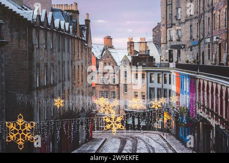 Decorazioni natalizie e i colorati negozi di Victoria Street nella città vecchia di Edimburgo in una mattina d'inverno dopo una fresca nevicata notturna. Foto Stock