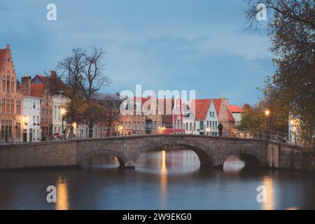 Un uomo si erge da solo sul Ponte di Carmers, nella splendida città vecchia di Bruges, in Belgio, al tramonto. Foto Stock