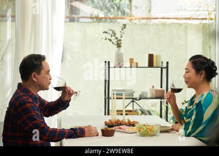 Coppia vietnamita anziana che cena e beve vino a casa Foto Stock