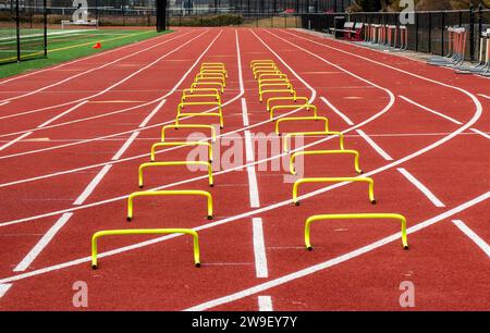 Due file di piccoli ostacoli gialli su una pista da corsa in corsie. Foto Stock