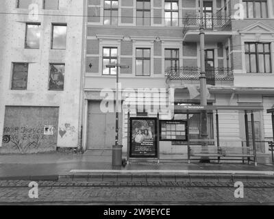 Un'immagine in bianco e nero di un edificio in mattoni con una panca bianca di fronte ad esso, situato in un ambiente urbano Foto Stock