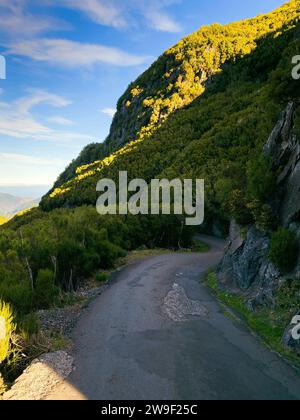 Una vista aerea di una pittoresca strada di campagna tortuosa che conduce giù per una collina, offrendo una vista mozzafiato della catena montuosa oltre Foto Stock