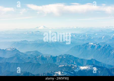 Ampia vista aerea delle catene montuose con il monte Baker in lontananza, da una finestra aerea. Foto Stock