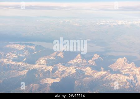 Grand Tetons si staglia maestosamente sotto, visto dal finestrino di un aereo passeggeri. Foto Stock