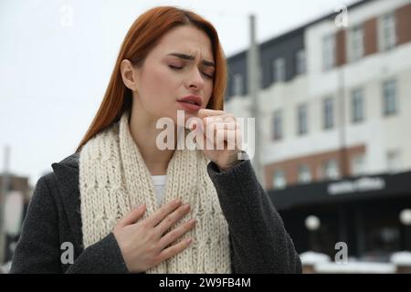 Bella giovane donna che tossisce all'aperto, spazio per il testo. Sintomi del raffreddore Foto Stock