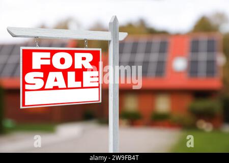 Cartello di vendita vicino a una bella casa all'aperto. Cartello rosso con le parole Foto Stock