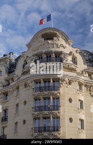 Hôtel Lutetia, Parigi, Francia |elegante facciata parigina con bandiera francese sotto un cielo blu con nuvole. Foto Stock