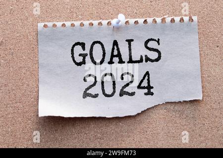 Risoluzioni di Capodanno 2024 sulla scrivania. elenco obiettivi 2024 con notebook, tazza di caffè, pianta su tavolo blu. Risoluzioni, piano, obiettivi, azione, lista di controllo, idea c Foto Stock