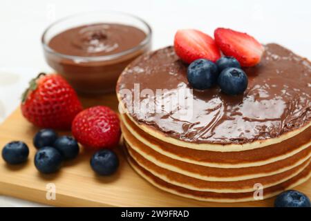 Pancake gustosi con pasta al cioccolato e frutti di bosco sul tavolo, primo piano Foto Stock