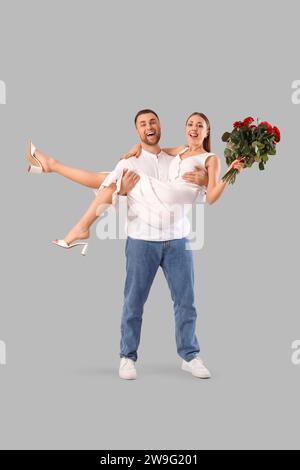 Coppia incantevole con bouquet di rose su sfondo grigio. Festa di San Valentino Foto Stock