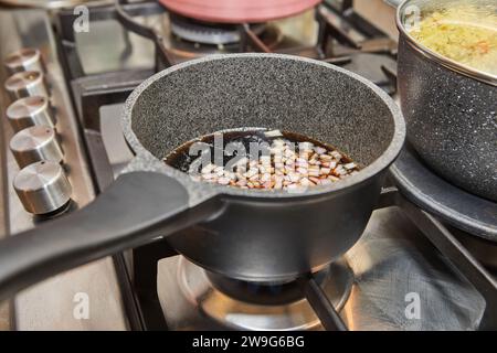 Cucina vivace con pentole e coperchi diversi su una stufa a gas, fiamme che bruciano, mentre il cibo delizioso viene preparato a casa, creando un ambiente accogliente e accogliente Foto Stock