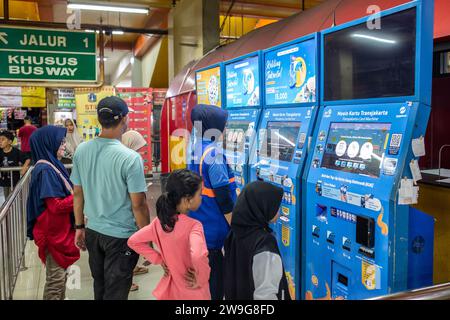 Giacarta, Indonesia - 24 dicembre 2023: Persone non identificate che acquistano biglietti dell'autobus da una biglietteria elettronica. Foto Stock