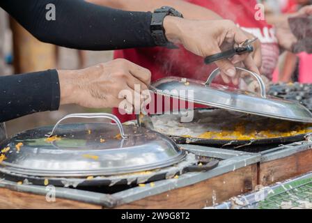 Pancake tailandese, mani maschili che preparano khanom krok i tradizionali dessert thailandesi dai sapori deliziosi sono popolari tra i thailandesi e i turisti intorno alla wor Foto Stock