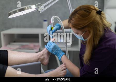 Primo piano sulle mani di un'estetista che esegue una pedicure su una donna matura. Foto Stock