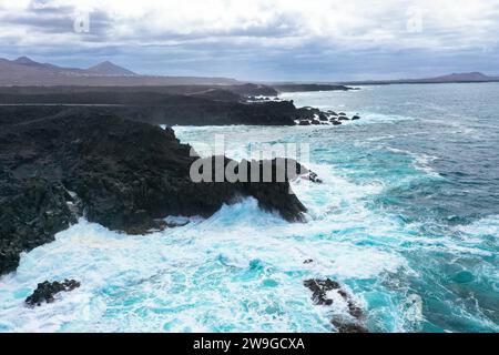 Vista panoramica aerea di Los Hervideros. Costa sudoccidentale, aspra costa vulcanica, surf forte, grotte marine, colline di lava rossa. Lanzarote, Isole Canarie, Spa Foto Stock