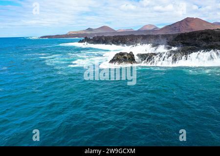 Vista panoramica aerea di Los Hervideros. Costa sudoccidentale, aspra costa vulcanica, surf forte, grotte marine, colline di lava rossa. Lanzarote, Isole Canarie, Spa Foto Stock