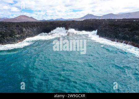 Vista panoramica aerea di Los Hervideros. Costa sudoccidentale, aspra costa vulcanica, surf forte, grotte marine, colline di lava rossa. Lanzarote, Isole Canarie, Spa Foto Stock