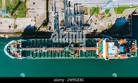 Enorme nave cargo al porto. Bunkeraggio, nave di rifornimento per il proseguimento del viaggio, sosta nel mezzo della rotta commerciale per rifornire la barca prima di trasportare ulteriormente le merci a destinazione. Vista aerea sopra la parte superiore del drone Foto Stock