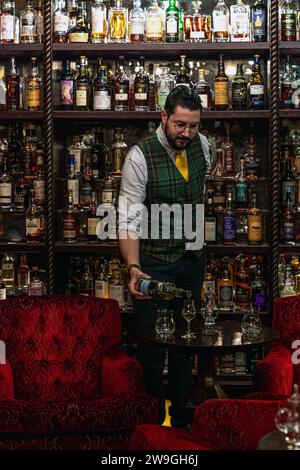 Il barman versa whisky al Bertie's Whisky Bar, Fife Arms, Braemar, Scozia. Foto Stock