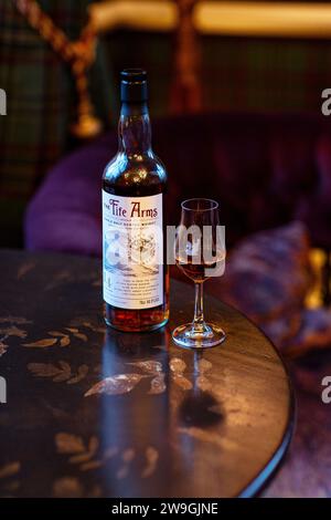 Bottiglia di whisky single malt con bicchiere di whisky e intimo sottofondo del soggiorno. Foto Stock