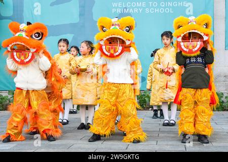 Gli studenti eseguono la danza del drago e del leone per dare il benvenuto al nuovo anno a Chongqing, Cina, 25 dicembre 2023. Foto Stock