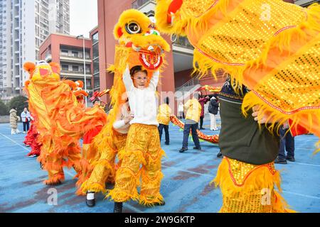 Gli studenti eseguono la danza del drago e del leone per dare il benvenuto al nuovo anno a Chongqing, Cina, 25 dicembre 2023. Foto Stock