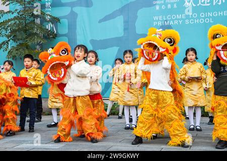 Gli studenti eseguono la danza del drago e del leone per dare il benvenuto al nuovo anno a Chongqing, Cina, 25 dicembre 2023. Foto Stock