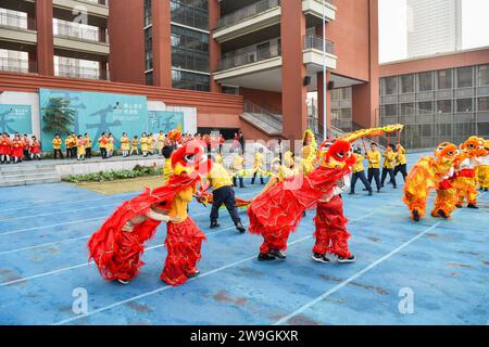 Gli studenti eseguono la danza del drago e del leone per dare il benvenuto al nuovo anno a Chongqing, Cina, 25 dicembre 2023. Foto Stock