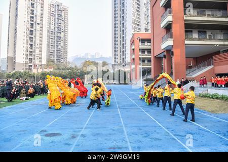 Gli studenti eseguono la danza del drago e del leone per dare il benvenuto al nuovo anno a Chongqing, Cina, 25 dicembre 2023. Foto Stock