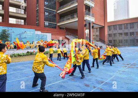 Gli studenti eseguono la danza del drago e del leone per dare il benvenuto al nuovo anno a Chongqing, Cina, 25 dicembre 2023. Foto Stock