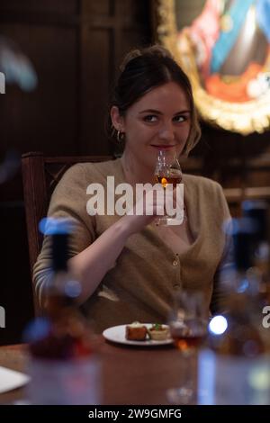 Giovane donna che sputa un bicchiere con whisky single malt Foto Stock