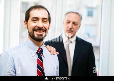 Senior manager che mette la mano sul sonoro di un collega Foto Stock