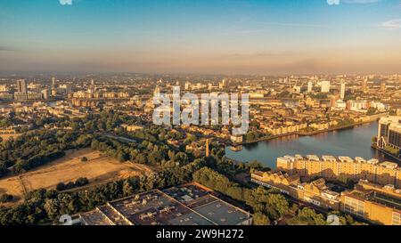 Vista aerea di un paesaggio urbano costiero caratterizzato da una rete di edifici con foreste lussureggianti e corsi d'acqua visibili sullo sfondo Foto Stock