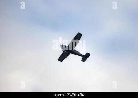 La silhouette di un aereo leggero è nel cielo nuvoloso di giorno Foto Stock