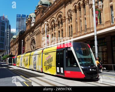 Guardate lungo George Street al Queen Victoria Building di Sydney, Australia, con un tram che vi aspetta alla fermata QVB del tram Foto Stock