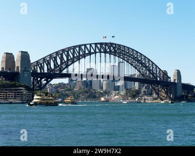 Vista del famoso Sydney Harbour Bridge che attraversa il porto, con North Sydney sullo sfondo e un traghetto che passa Foto Stock